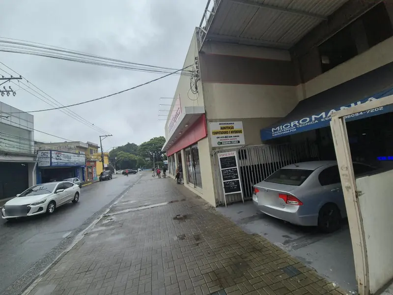 Calçada da Av. Nove de Julho em frente à Micromania, com a placa amarela na entrada e o toldo azul no fundo do corredor